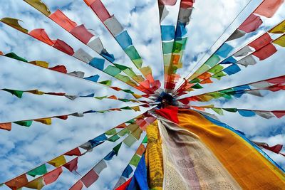 Low angle view of prayer flags at temple against cloudy sky