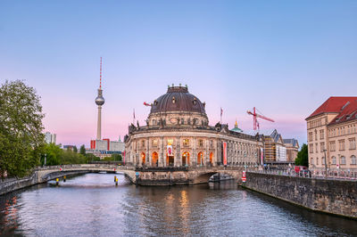 Bridge over river in city against clear sky