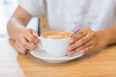 Midsection of woman holding coffee cup on table