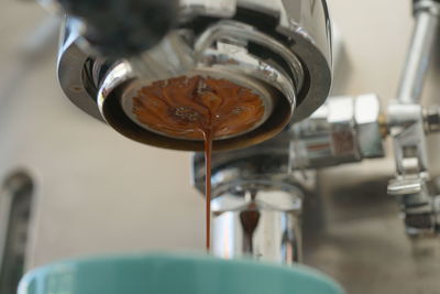 Close-up of machinery pouring coffee in cup at cafe