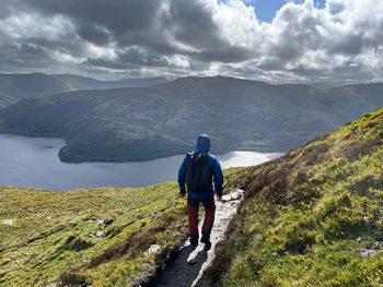 Rear view of man standing on mountain against sky