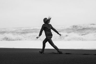 Playful person running along sea beach monochrome scenic photography