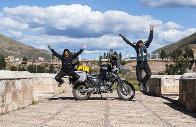 Motorcyclists celebrating on bridge over urubamba river, peru