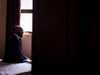 Side view of a man looking through window