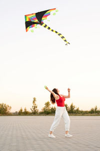 Full length of woman flying kite against sky