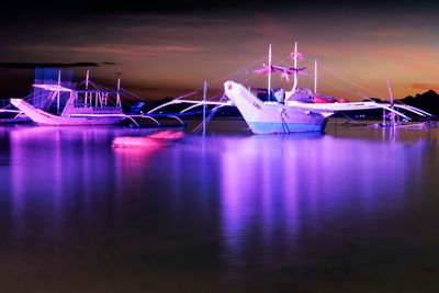 Boats moored at harbor against sky at night