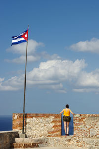 Rear view of man standing by building against sky