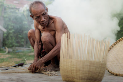 Portrait of shirtless man sitting outdoors