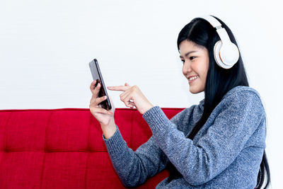 Young woman using phone while sitting on sofa