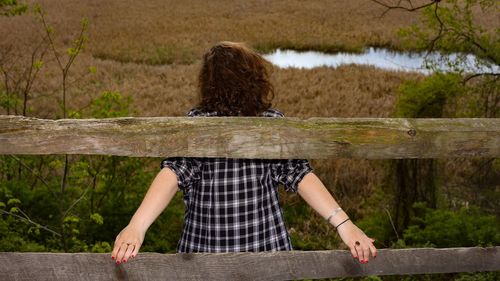 Rear view of woman leaning off a wooden banister on a cliff edge 