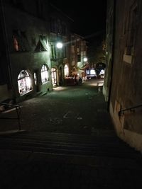 Illuminated street amidst buildings in city at night