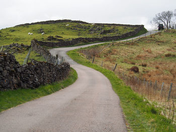 Road amidst field against sky