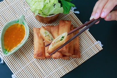 Cropped hand holding food with chopsticks