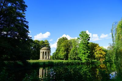 View of trees by lake against blue sky