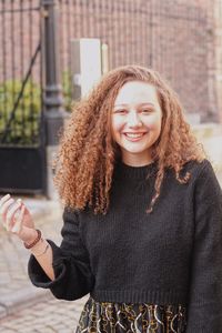 Portrait of smiling young woman standing on city street