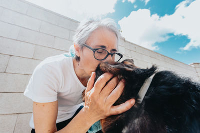 Woman kissing dog against wall