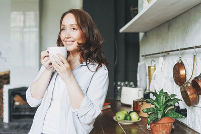 Woman holding coffee cup at home