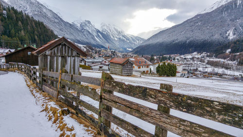 Wooden fence on snow covered field in village