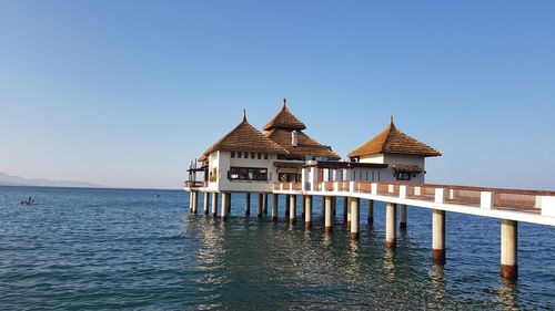 Building by sea against clear blue sky