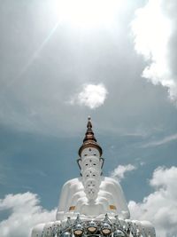 Low angle view of buddha images against sky on sunny day