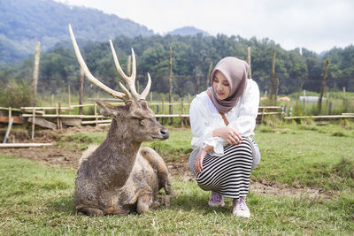 Beautiful asian girl playing with a deer at rancaupas, ciwidey, bandung, indonesia