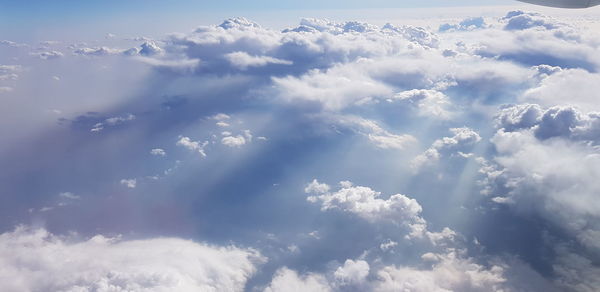 Low angle view of sunlight streaming through clouds