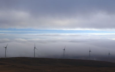 Low angle view of windmill on field against sky