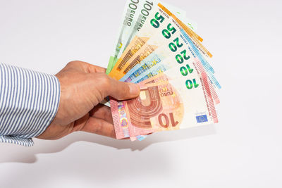 Close-up of hand holding paper over white background