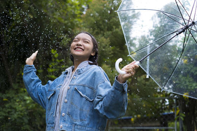 Woman standing with umbrella in rain