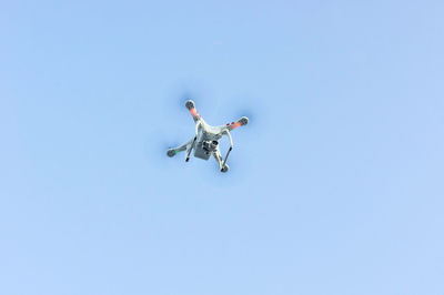 Low angle view of drone flying against clear blue sky
