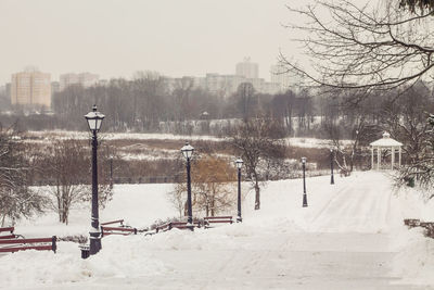 Snow covered field by street against sky