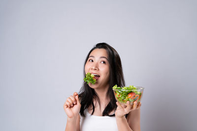 Portrait of woman eating food against white background