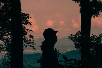 Silhouette woman standing by tree against sky during sunset