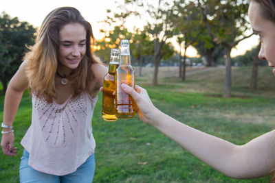 Friends toasting beer bottles at park