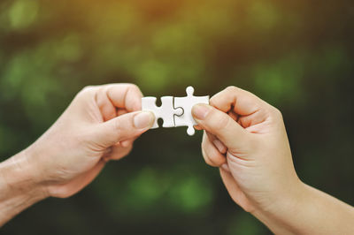 Cropped hands of people holding jigsaw piece