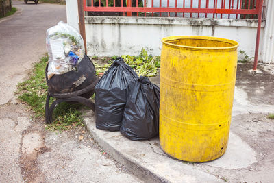 Garbage bin on sidewalk by street in city
