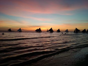 Silhouette boats on beach against sky during sunset