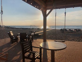 Chairs and table by sea against sky