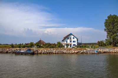 Houses by lake against sky