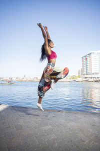 Woman jumping in city against clear sky