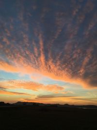 Scenic view of dramatic sky over silhouette landscape during sunset