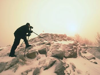 Silhouette of photographer with tripod in the fog.. photographer works in foggy winter landscape