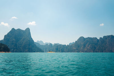 Scenic view of sea by mountains against sky