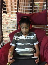Boy using digital tablet while sitting on sofa at home