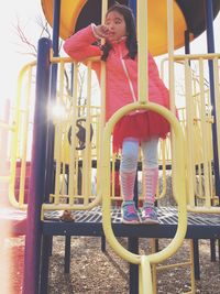 Thoughtful girl standing on outdoor playing equipment