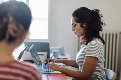 Focused ethnic woman typing on laptop working in office