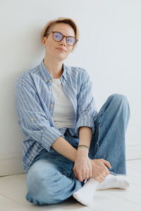 Woman in a blue shirt with short hair poses. brooding millennial woman in a white studio