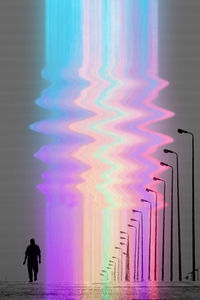 Silhouette person standing against illuminated wall