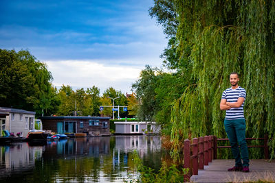 Portrait of man standing by lake against sky