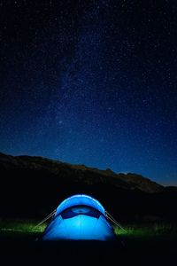 Tent against mountain range at night